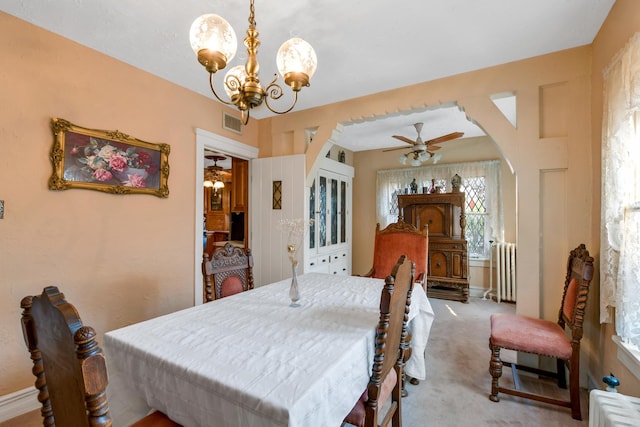 dining room with ceiling fan with notable chandelier, light colored carpet, and radiator heating unit