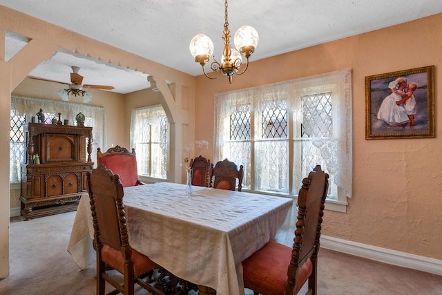 carpeted dining room with ceiling fan with notable chandelier