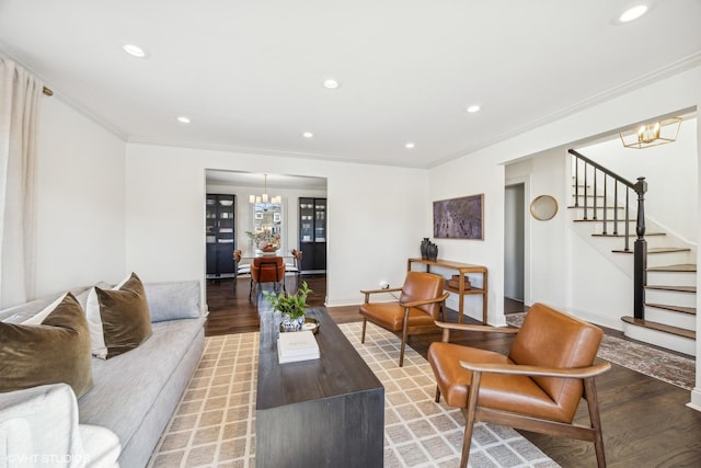 living room featuring hardwood / wood-style flooring, ornamental molding, and a notable chandelier