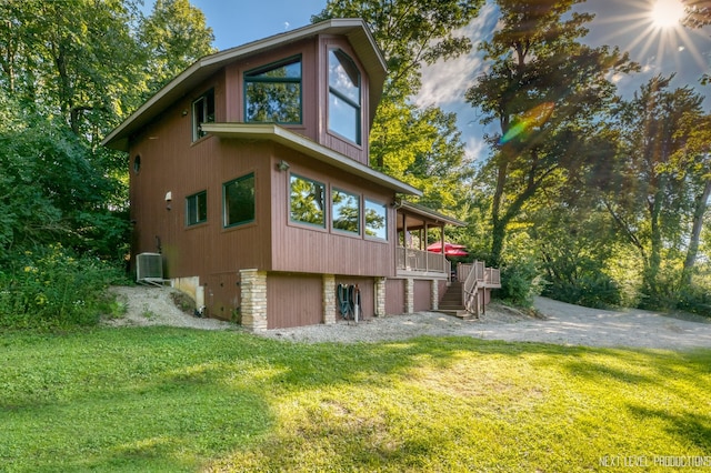 view of side of home featuring a wooden deck, a lawn, and central AC