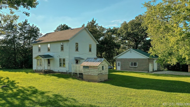 rear view of house featuring a lawn and an outdoor structure