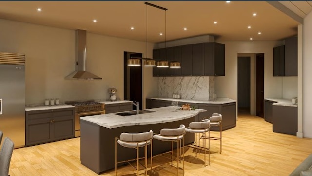 kitchen featuring a kitchen island with sink, sink, wall chimney exhaust hood, a breakfast bar area, and high quality appliances