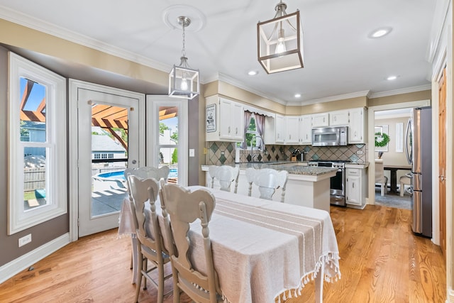 dining room with crown molding and light hardwood / wood-style floors