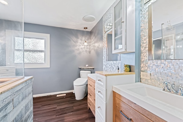 bathroom featuring toilet, hardwood / wood-style flooring, decorative backsplash, and vanity