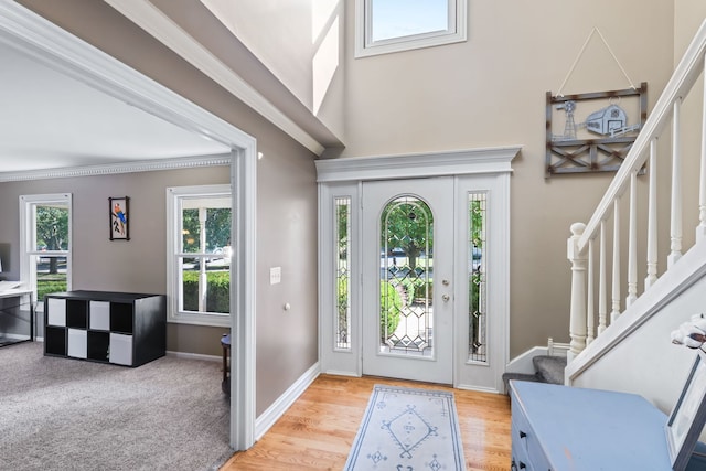 foyer entrance with light hardwood / wood-style flooring and ornamental molding