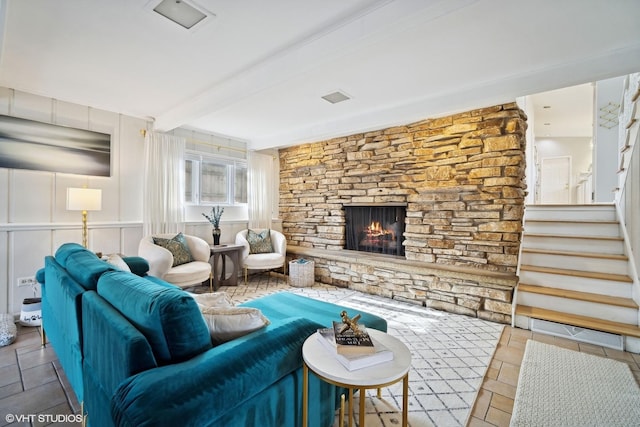 living room with beamed ceiling and a stone fireplace