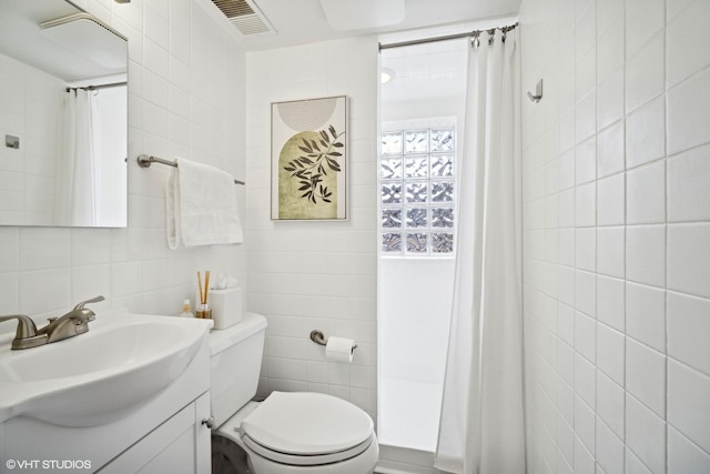 bathroom featuring tasteful backsplash, vanity, toilet, and tile walls