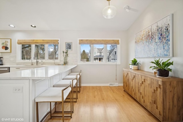 kitchen featuring pendant lighting, sink, a breakfast bar, white cabinetry, and kitchen peninsula