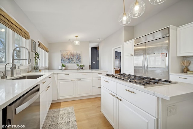 kitchen featuring stainless steel appliances, sink, pendant lighting, and white cabinets