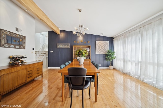 dining space featuring beamed ceiling, a notable chandelier, and light wood-type flooring