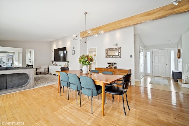 dining area featuring a wealth of natural light, a chandelier, lofted ceiling with beams, and light wood-type flooring