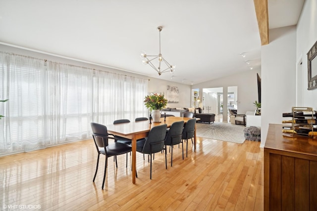 dining area featuring light hardwood / wood-style flooring, a chandelier, and vaulted ceiling