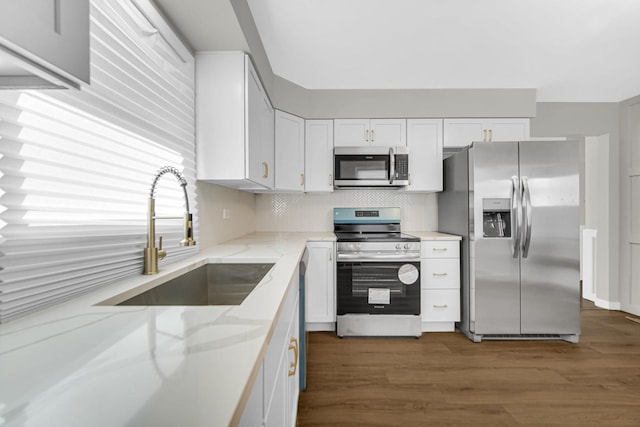 kitchen featuring appliances with stainless steel finishes, light stone countertops, sink, and white cabinets