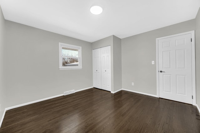 unfurnished bedroom featuring dark hardwood / wood-style floors and a closet