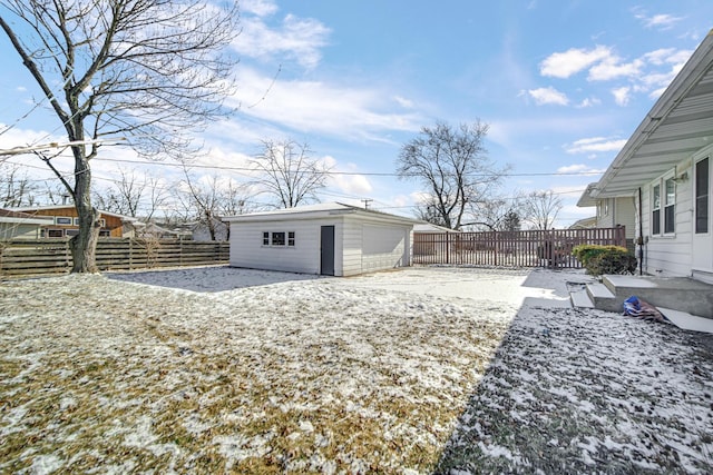 snowy yard featuring a garage and an outbuilding