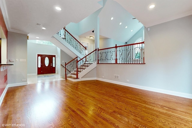 unfurnished living room with crown molding, hardwood / wood-style floors, and a towering ceiling