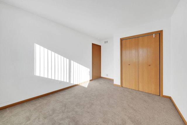 unfurnished bedroom with a closet and light carpet