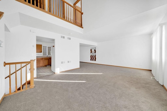 unfurnished living room with light carpet and a towering ceiling