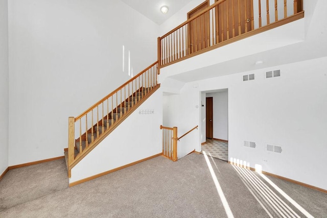 stairs featuring carpet floors and a high ceiling