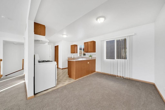 kitchen featuring white range with gas stovetop, sink, kitchen peninsula, and light carpet