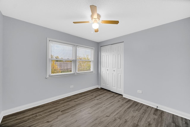 unfurnished bedroom featuring ceiling fan, a closet, and dark hardwood / wood-style flooring