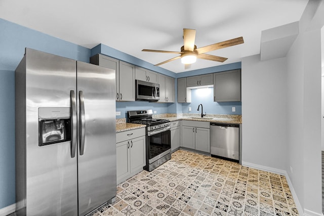 kitchen with ceiling fan, sink, light stone countertops, gray cabinets, and stainless steel appliances