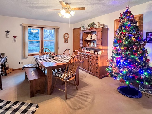 dining space with ceiling fan, light colored carpet, and a textured ceiling