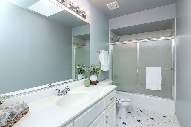 full bathroom with vanity, a skylight, bath / shower combo with glass door, and toilet