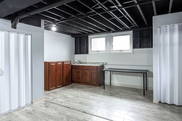 basement with sink and light hardwood / wood-style flooring