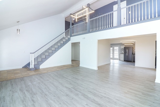 unfurnished living room featuring hardwood / wood-style flooring and a towering ceiling