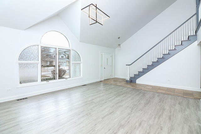 unfurnished living room with high vaulted ceiling and light hardwood / wood-style floors