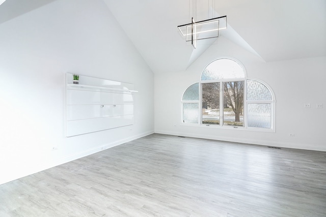 empty room with light wood-type flooring and vaulted ceiling