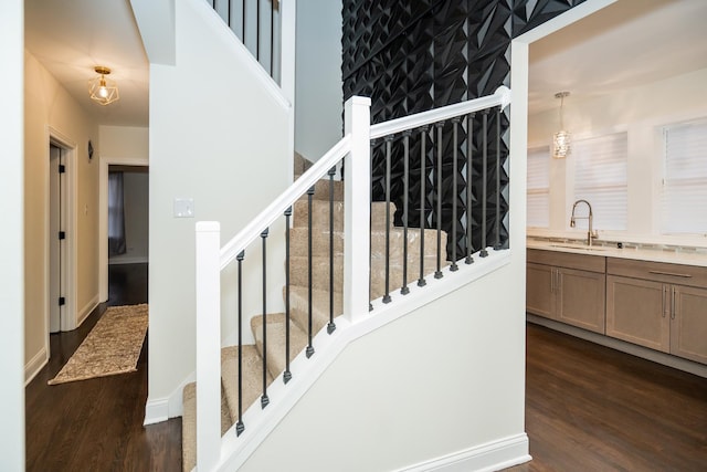 stairway featuring sink, wood-type flooring, and a chandelier