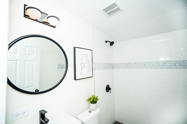 bathroom with sink, toilet, and tiled shower