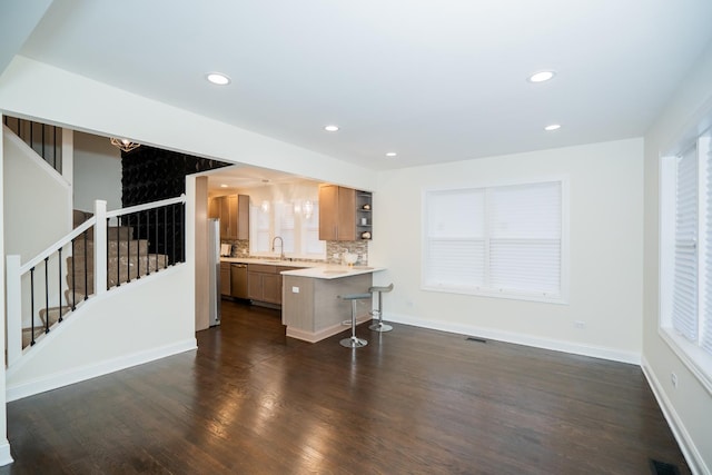 kitchen featuring a kitchen bar, dishwasher, decorative backsplash, sink, and dark hardwood / wood-style floors