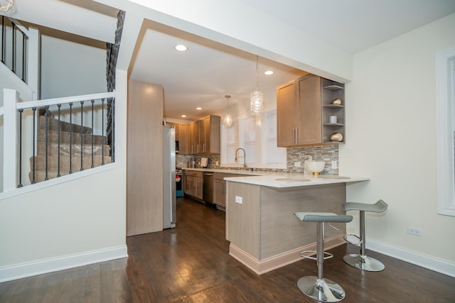 kitchen featuring appliances with stainless steel finishes, a kitchen bar, decorative light fixtures, decorative backsplash, and kitchen peninsula