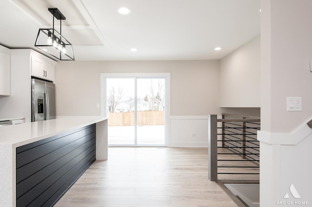 kitchen featuring light hardwood / wood-style floors, white cabinets, hanging light fixtures, and stainless steel fridge