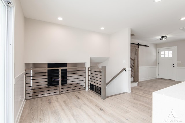 unfurnished living room featuring a barn door and light hardwood / wood-style flooring