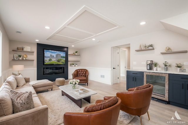 living room featuring a fireplace, light wood-type flooring, and beverage cooler