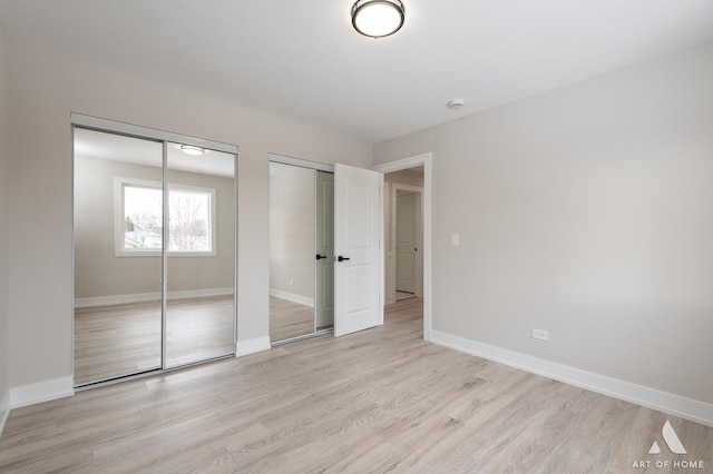 unfurnished bedroom with multiple closets and light hardwood / wood-style floors