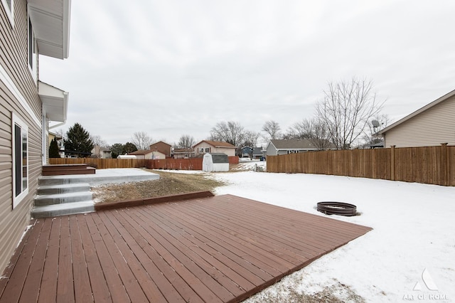 snow covered deck with a storage shed and a fire pit