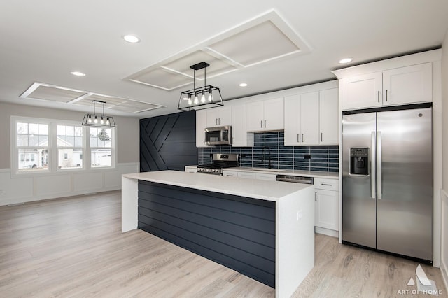 kitchen featuring pendant lighting, sink, white cabinetry, a kitchen island, and stainless steel appliances