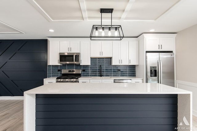 kitchen with sink, white cabinets, light wood-type flooring, pendant lighting, and stainless steel appliances