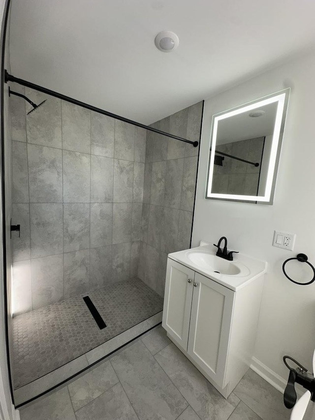 bathroom with a tile shower and vanity