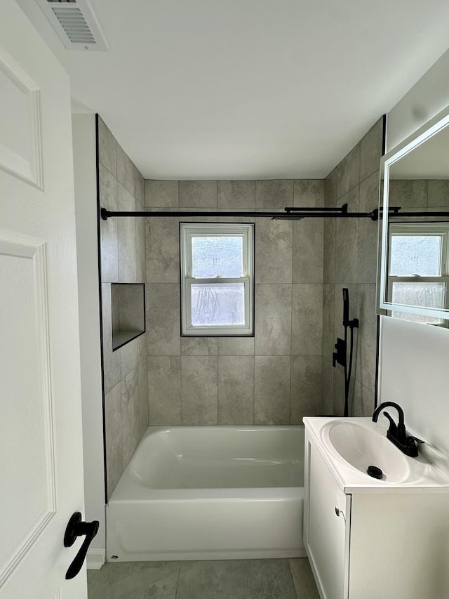 bathroom featuring vanity, plenty of natural light, tile patterned floors, and tiled shower / bath