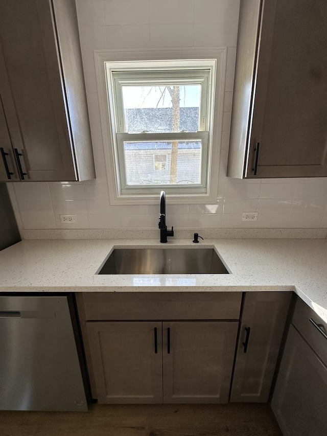 kitchen featuring light stone countertops, sink, stainless steel dishwasher, and backsplash