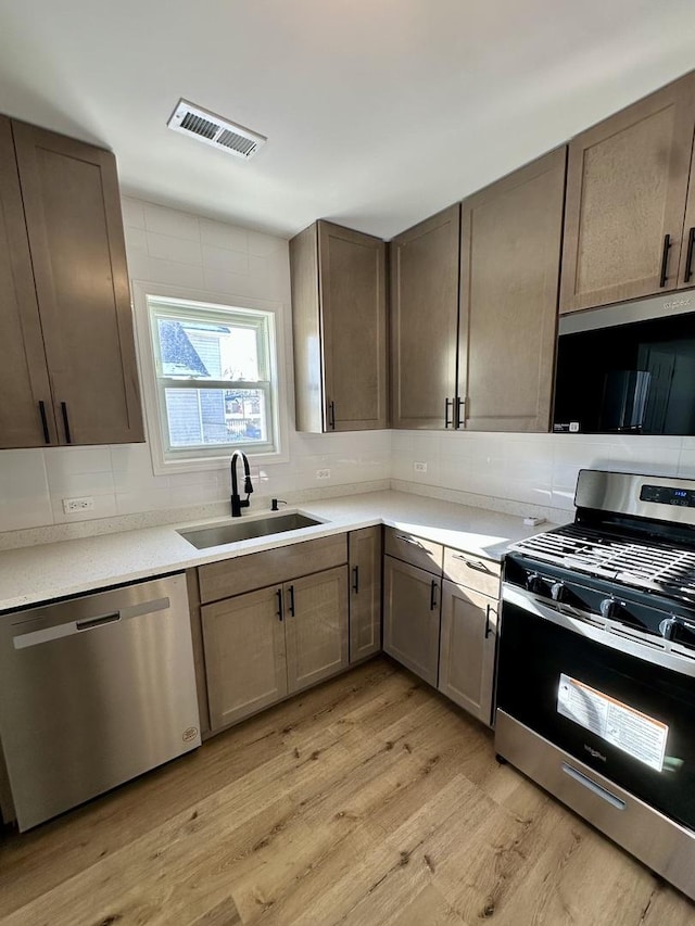 kitchen featuring sink, backsplash, light hardwood / wood-style flooring, and stainless steel appliances