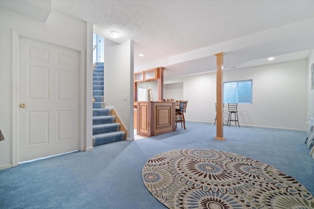 basement featuring light colored carpet, bar area, and a textured ceiling