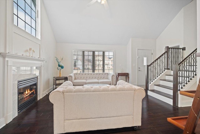 living room featuring dark hardwood / wood-style flooring, a high end fireplace, high vaulted ceiling, and ceiling fan