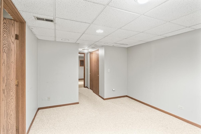 carpeted empty room with a drop ceiling